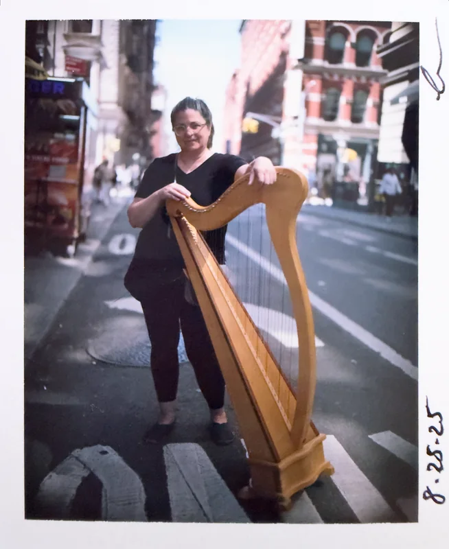 Mia Theodoratus with a harp on a New York street, Polaroid dated 8-25-25