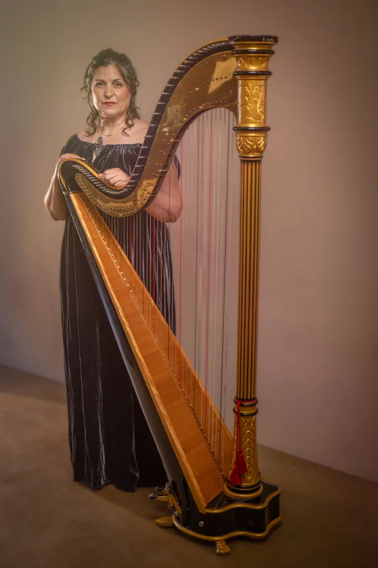 Mia Theodoratus in a dark velvet gown beside a gold concert harp
