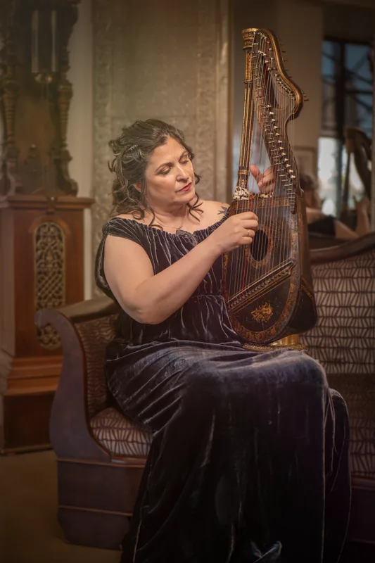 Mia Theodoratus in a velvet gown playing her dital harp
