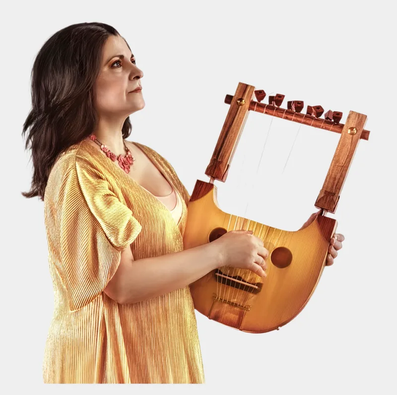 Mia Theodoratus in a gold dress holding an ancient Greek lyre
